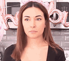 a woman wearing a pink crown is standing in front of a microwave and balloons .