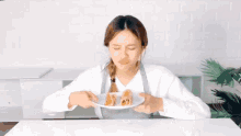 a woman wearing an apron is holding a plate of food and making a face