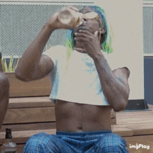 a man with green hair drinking from a bottle