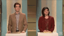 a man and a woman are standing next to each other on a snl stage