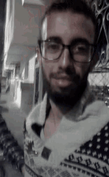 a man with glasses and a beard is wearing a sweater .