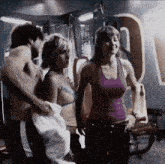 a woman in a purple tank top stands next to a man in a gym