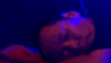 a woman is singing into a microphone in a dark room with glow in the dark paint on her body .
