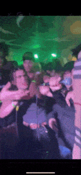 a group of people are standing in a room with green lights .