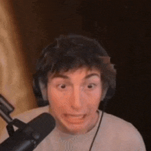 a man is making a funny face while sitting in front of a microphone .