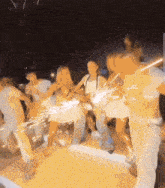 a group of people are dancing with sparklers in their hands .