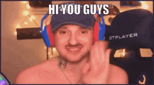 a shirtless man wearing headphones and a hat is waving at the camera .
