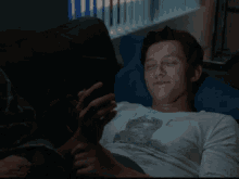 a man wearing a t-shirt with a picture of a man on it is laying on a couch .