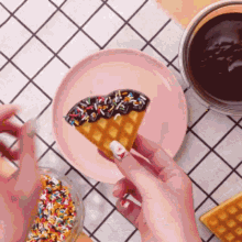 a person is holding a waffle with chocolate and sprinkles on it