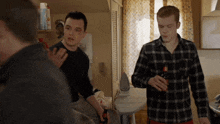 a man in a plaid shirt is holding a bottle