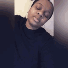 a woman wearing a black shirt and earrings is smiling with her eyes closed
