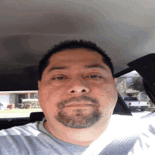 a man with a beard is sitting in a car looking at the camera