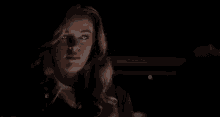 a woman is standing in a dark room with smoke coming out of her hand .