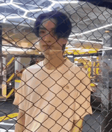 a man is standing behind a chain link fence in a gym .
