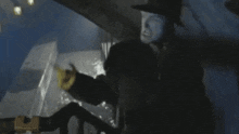 a man in a black hat stands in a dark room with his mouth open