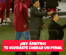 a man in a suit stands on a soccer field with the words hey arbitro te olvidaste cobrar un penal