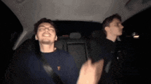 two men are sitting in the back seat of a car dancing .