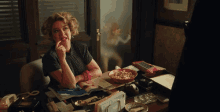 a woman sitting at a desk with a bowl of cereal in front of her