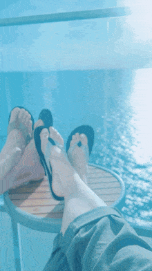 a man and a woman 's feet rest on a small table overlooking the ocean