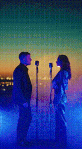 a man and a woman are standing next to each other and singing into microphones .