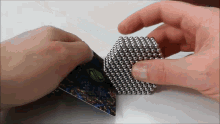 a person is holding a cube of magnetic balls and a card