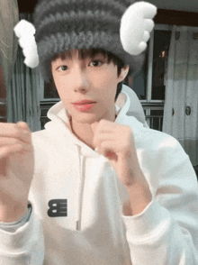 a young boy wearing a white hoodie and a knitted hat