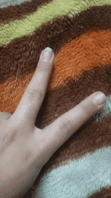 a woman 's hand is laying on a striped blanket and her nails are painted white