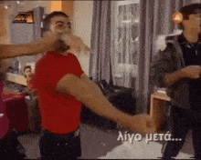a man in a red shirt is being punched by another man in a room