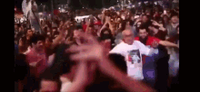a crowd of people are dancing at a party and one of them is wearing a shirt with a picture of a girl on it .