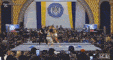 a crowd of people watching a wrestling match in front of a flag that says ukraine