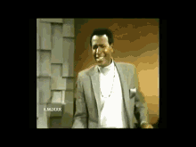 a man in a suit and white shirt is dancing in a room .