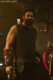 a man with a beard is wearing a black tank top and red gloves