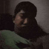 a man in a green shirt is laying in a dark room