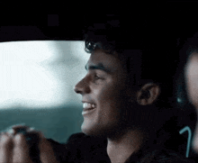a man is smiling while driving a car with another man .