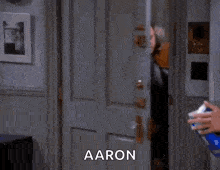 a man in a coat is standing in a doorway and says aaron .