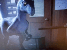 a dinosaur in a room with a calendar on the wall behind it