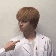 a man in a white coat is pointing at another man .
