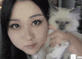 a close up of a woman holding a cat with a purple heart in the background