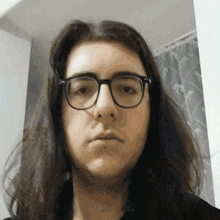 a woman with long hair and glasses looks at the camera with a serious look on her face