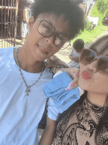 a woman wearing sunglasses and a necklace with a cross on it kisses a boy