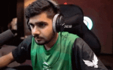 a man wearing headphones and a green shirt is sitting in a chair .