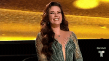 a woman in a green dress is smiling in front of a yellow background