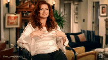 a woman is sitting in a wheelchair in a living room holding her chest .