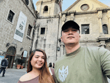 a man and a woman pose for a photo in front of a building