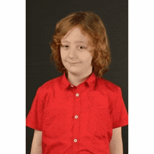 a young boy with red hair is wearing a red shirt and smiling