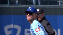 a baseball player wearing a kc hat and sunglasses is smiling