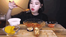 a woman is sitting at a table with chopsticks eating food