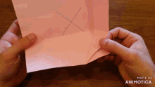 a person is holding a piece of pink paper with an x on it