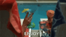 a person is sitting by a pool with a drink in their hand and the words `` enjoy ! ''