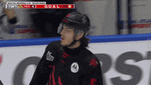 a hockey player stands in front of a scoreboard that says ' goal ' on it